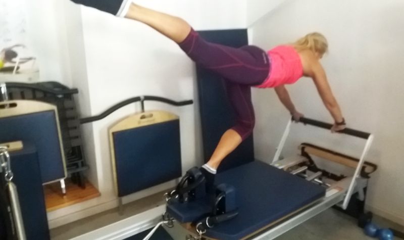 Woman performing Knee Stretches on Pilates Reformer